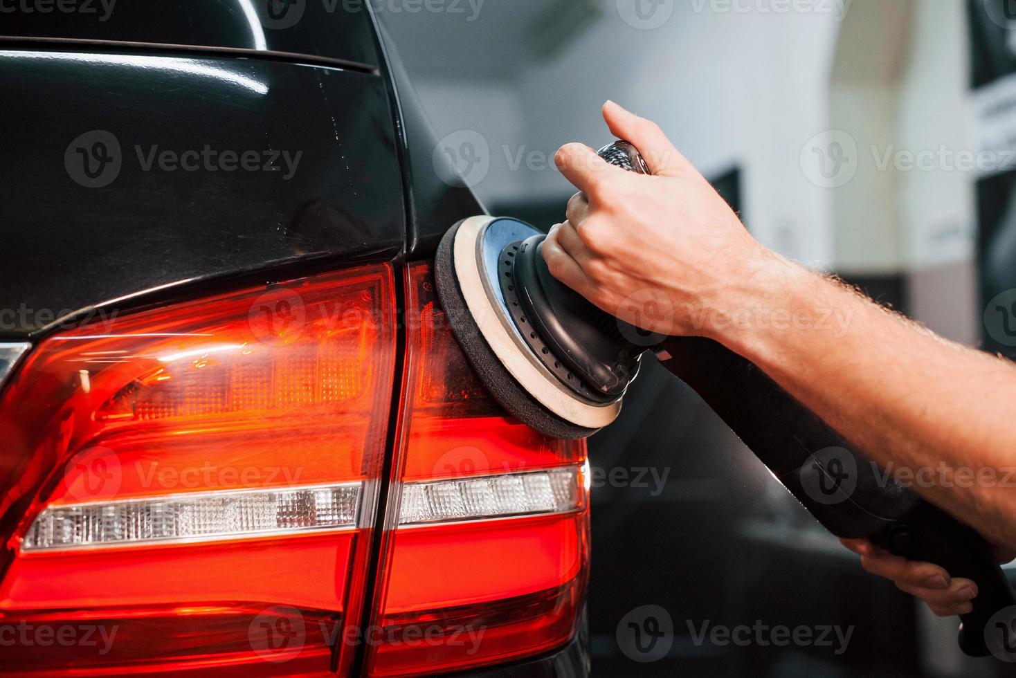 Guy polishing surface of vehicle. Modern black automobile get cleaned