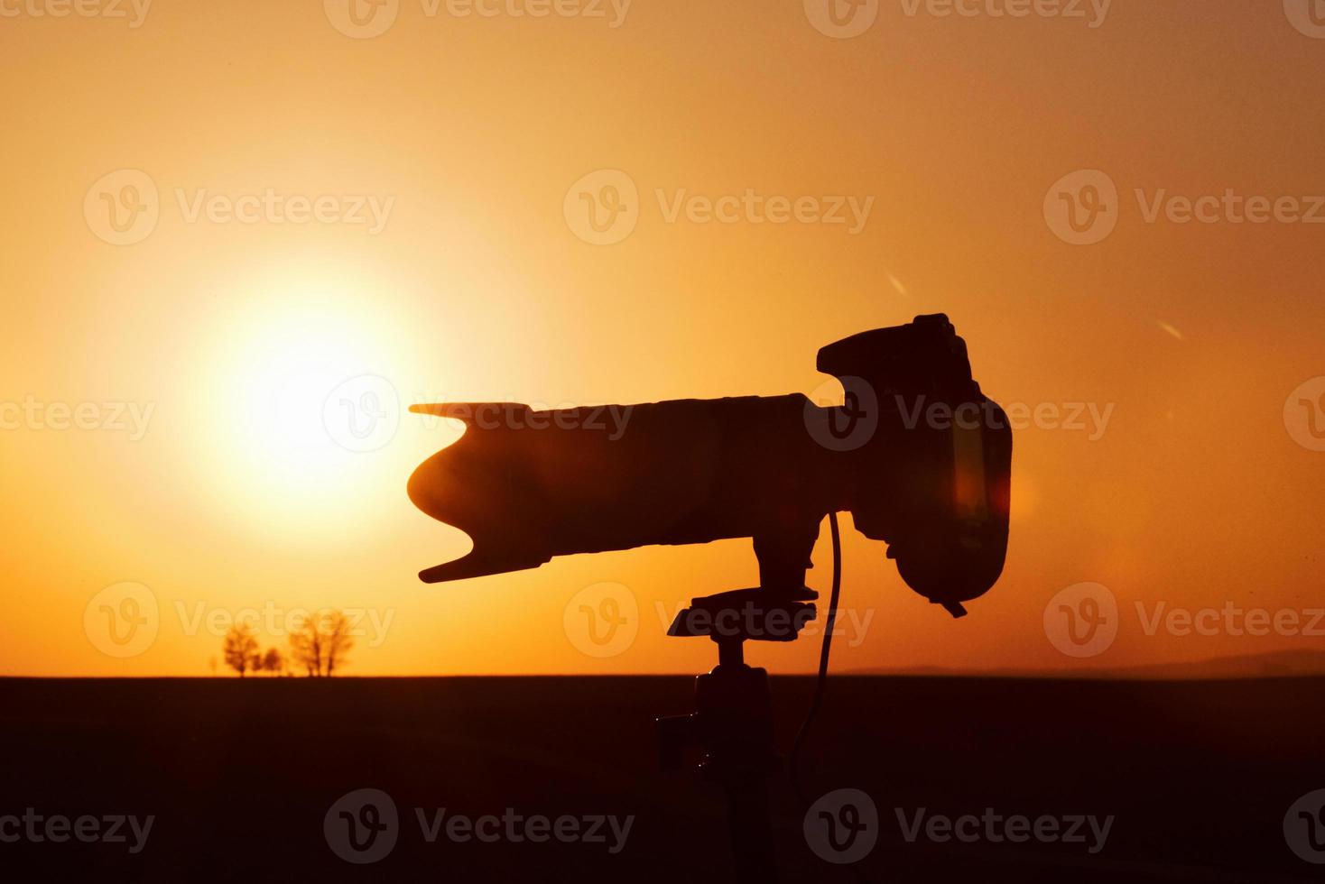 Side view of camera on tripod. Beautiful landscape with field illuminated by sunlight. In Moravia photo