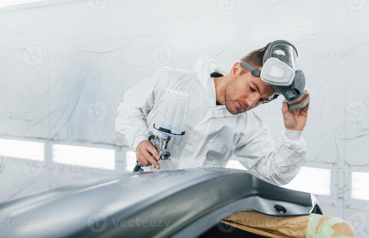 Painting the car. Man in uniform is working in the auto service photo