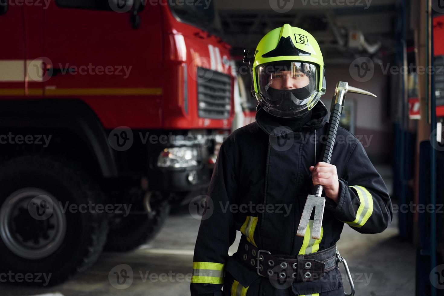 Male firefighter in protective uniform standing near truck photo