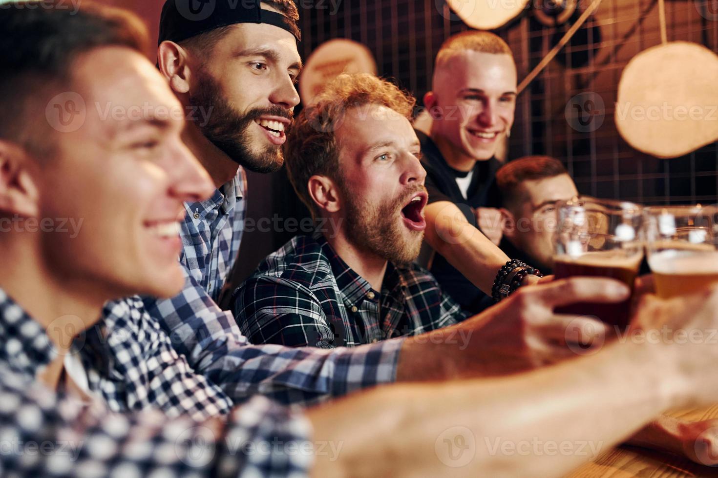 Fans cheer and shout. Group of people together indoors in the pub have fun at weekend time photo