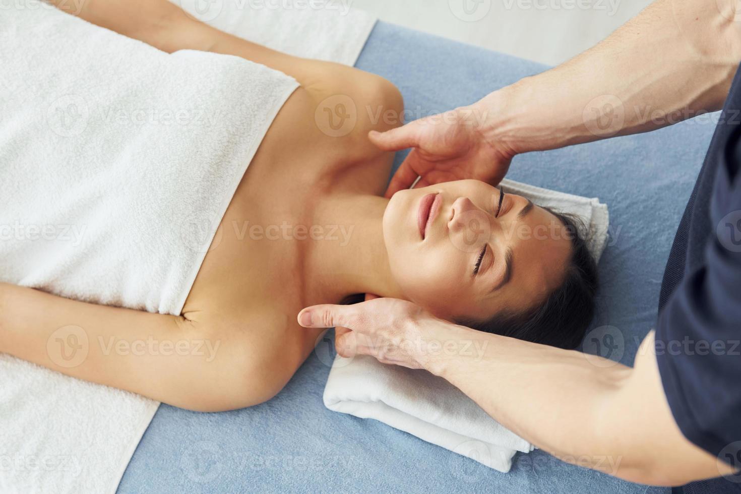 Young woman is lying down when man doing massage of her body at spa photo