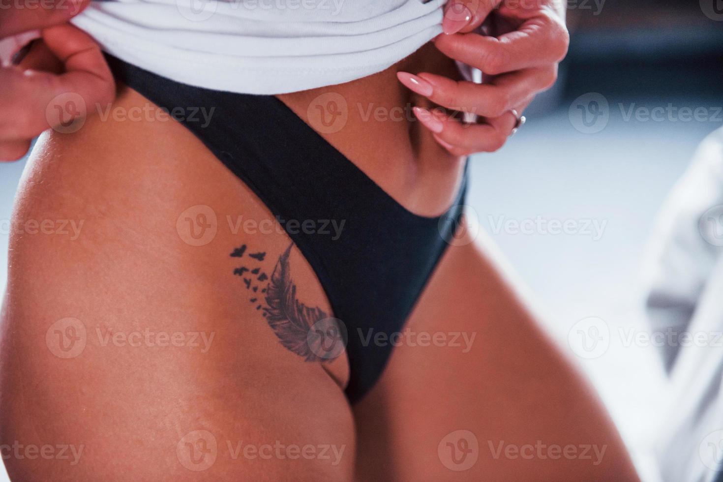 vista de cerca del cuerpo de la mujer caliente en lencería con tatuaje en la pierna en el interior foto