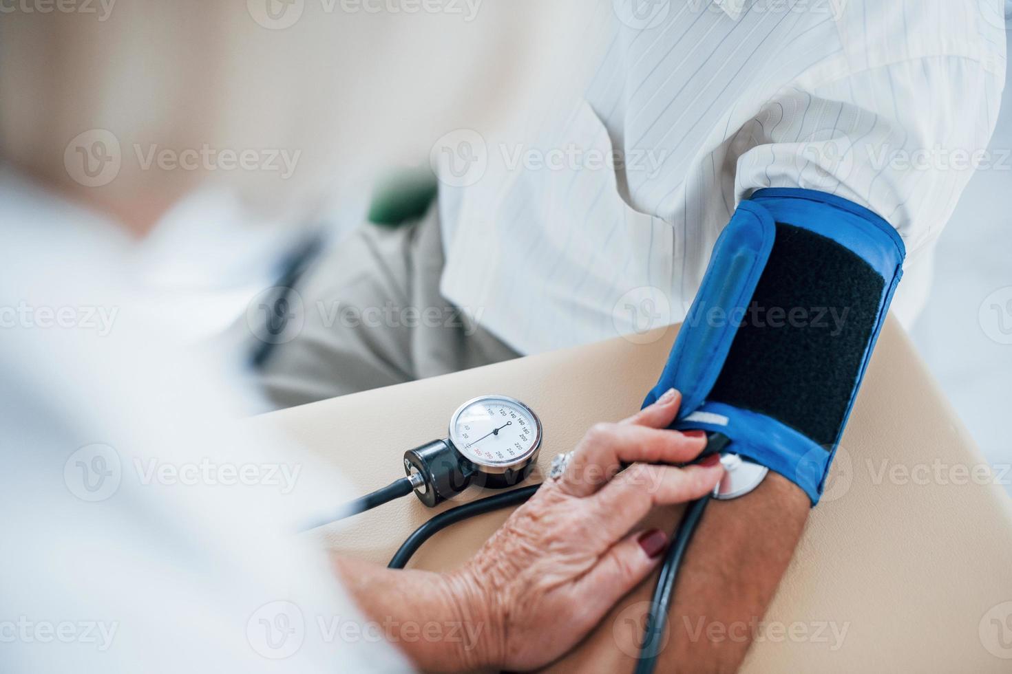 vista de cerca doctora usa tonómetro para medir la presión arterial al hombre mayor foto