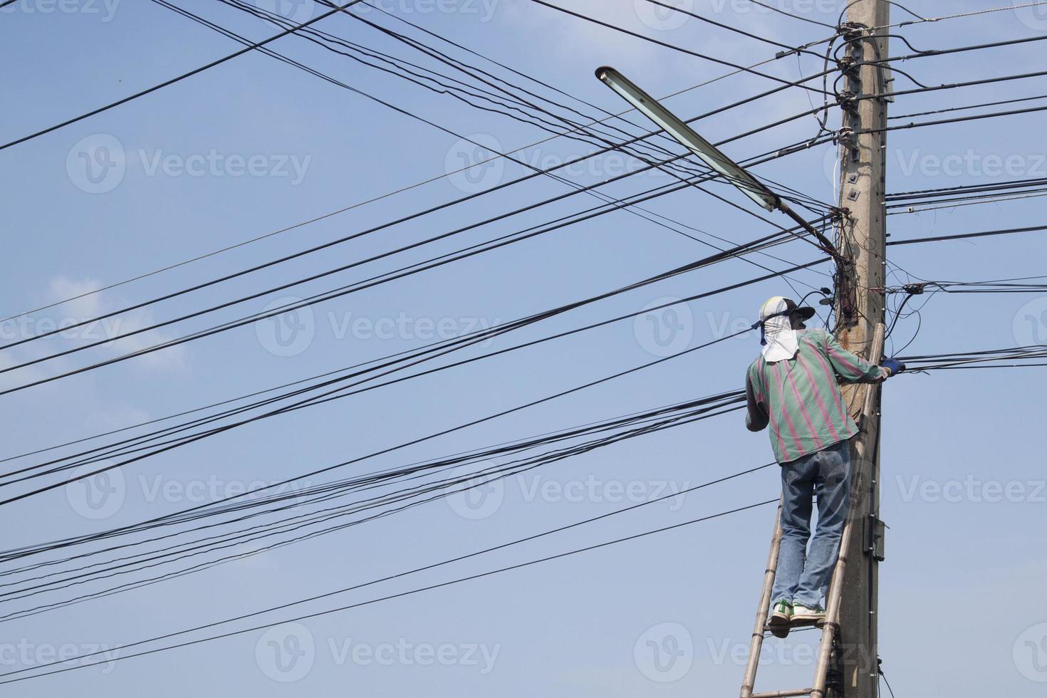 reparar el cable de señal de internet con escaleras de bambú que son muy riesgosas. foto