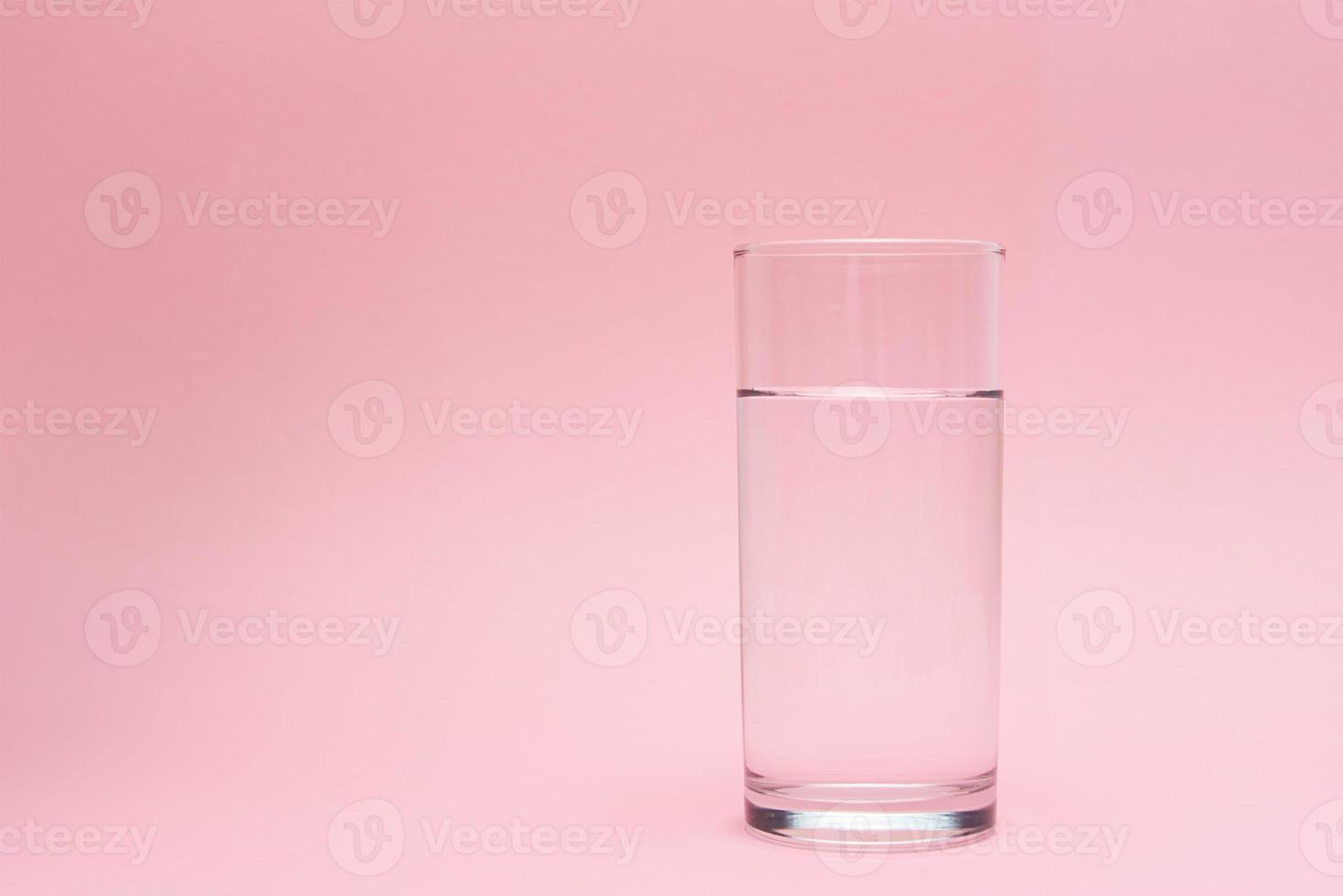 Glass of water on a pink background photo