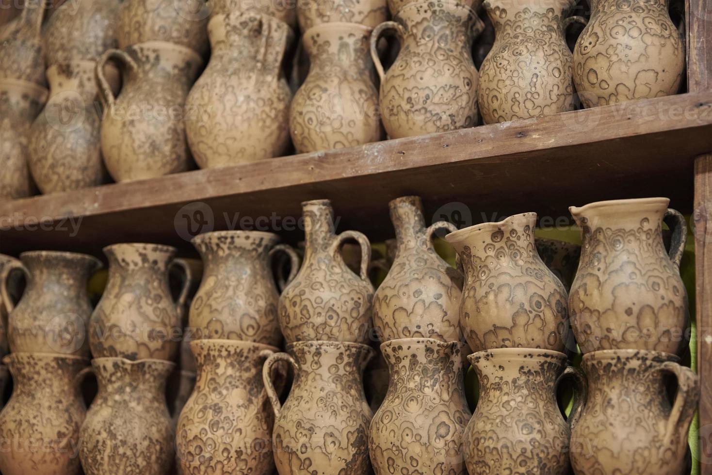 muchas jarras de arcilla hechas a mano en la estantería del taller foto