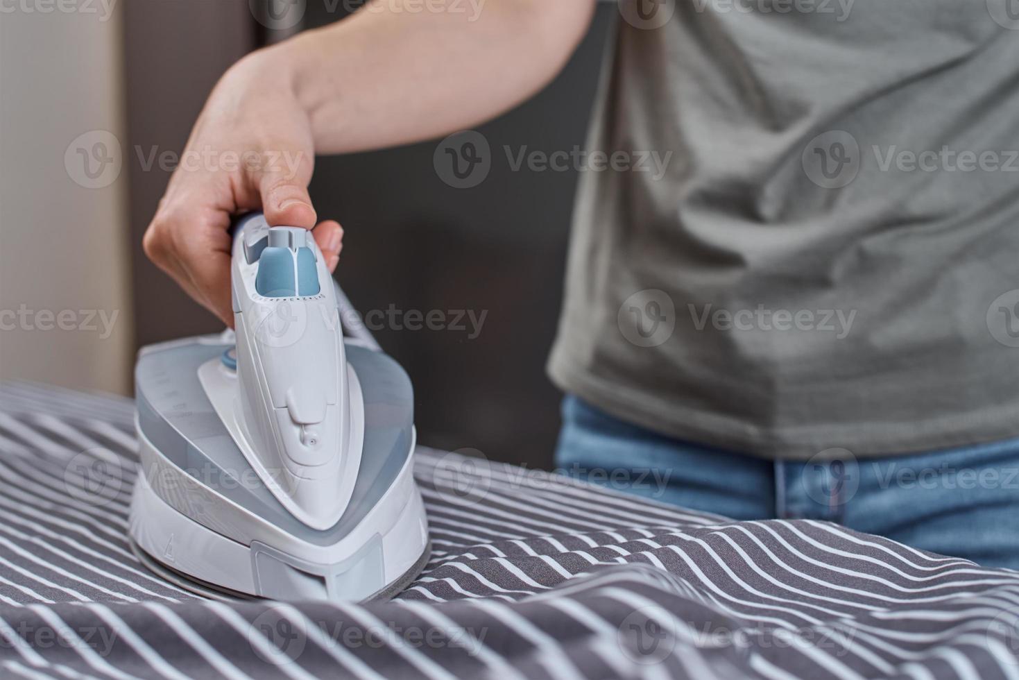 Woman ironing clothes on the ironing board with modern iron photo
