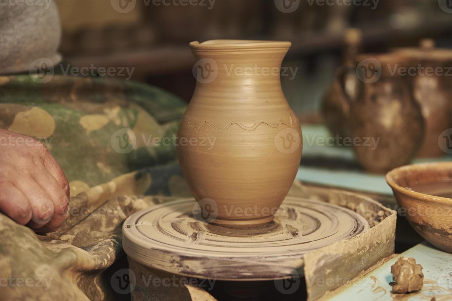 olla de barro en el torno de alfarero en el interior del taller foto