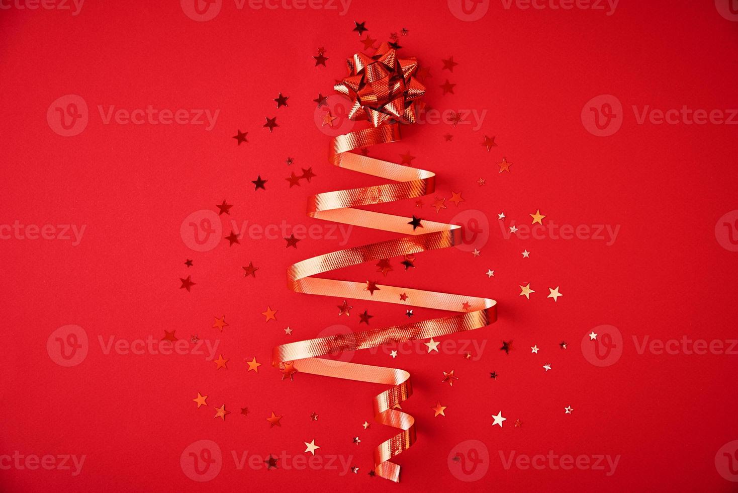 Christmas tree made from festive ribbon and confetti on a red background photo