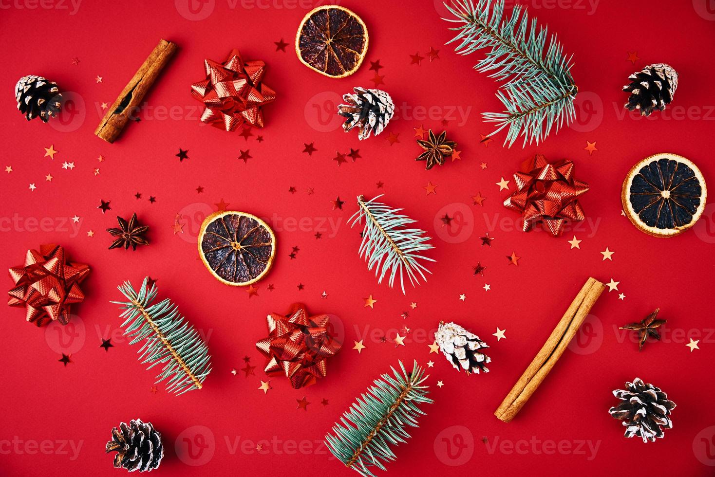 Fir branches, pine cones, dried fruits and festive confetti on a red background photo