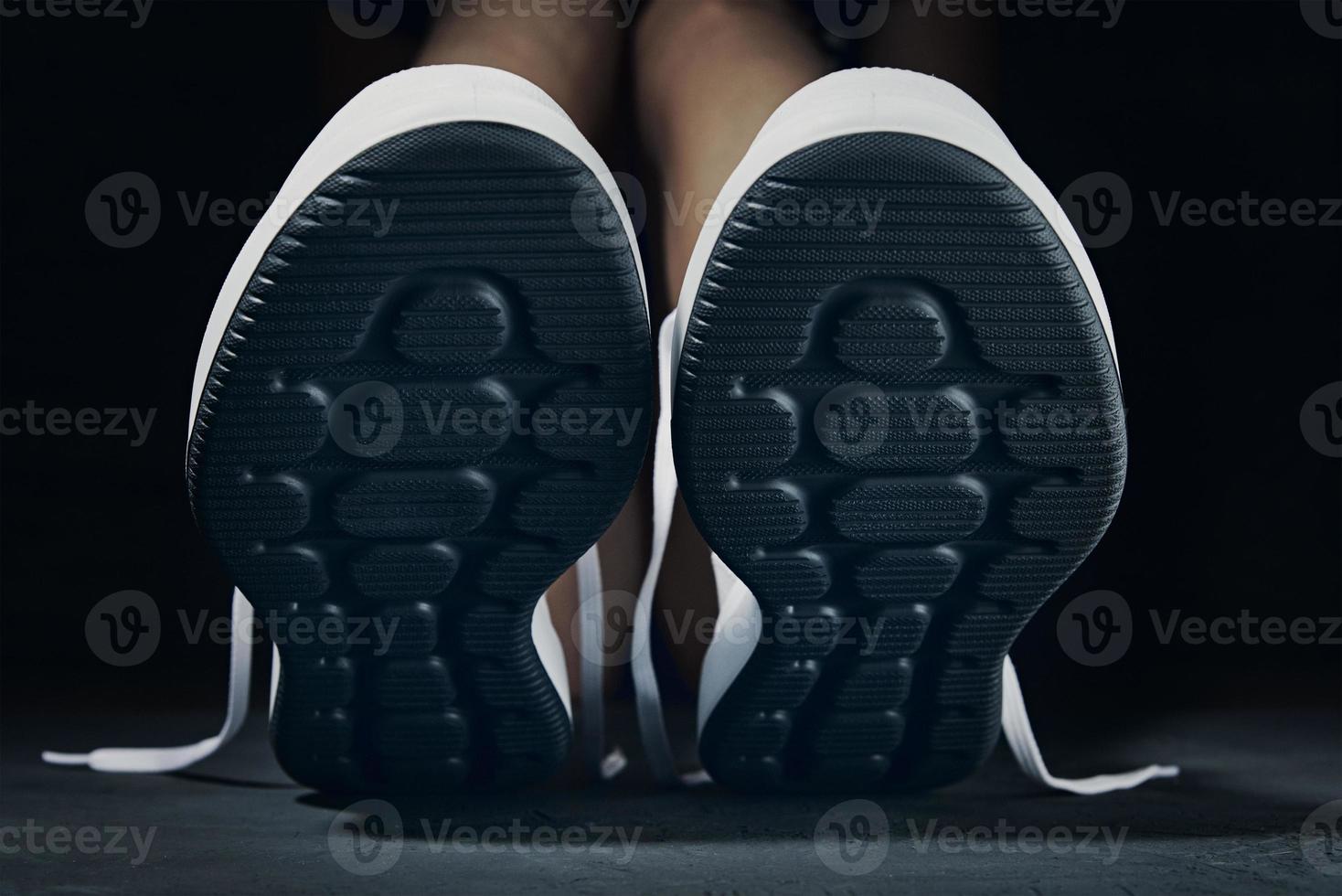 Woman in sport shoes sits on floor in gym photo