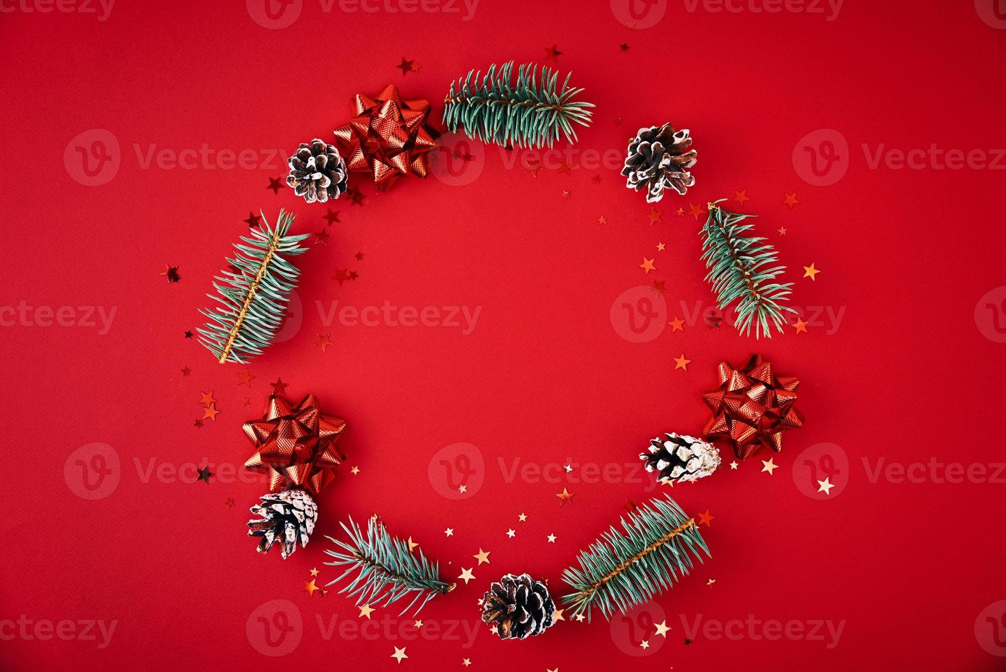 Wreath made of fir tree branches and festive pine cones on red background photo