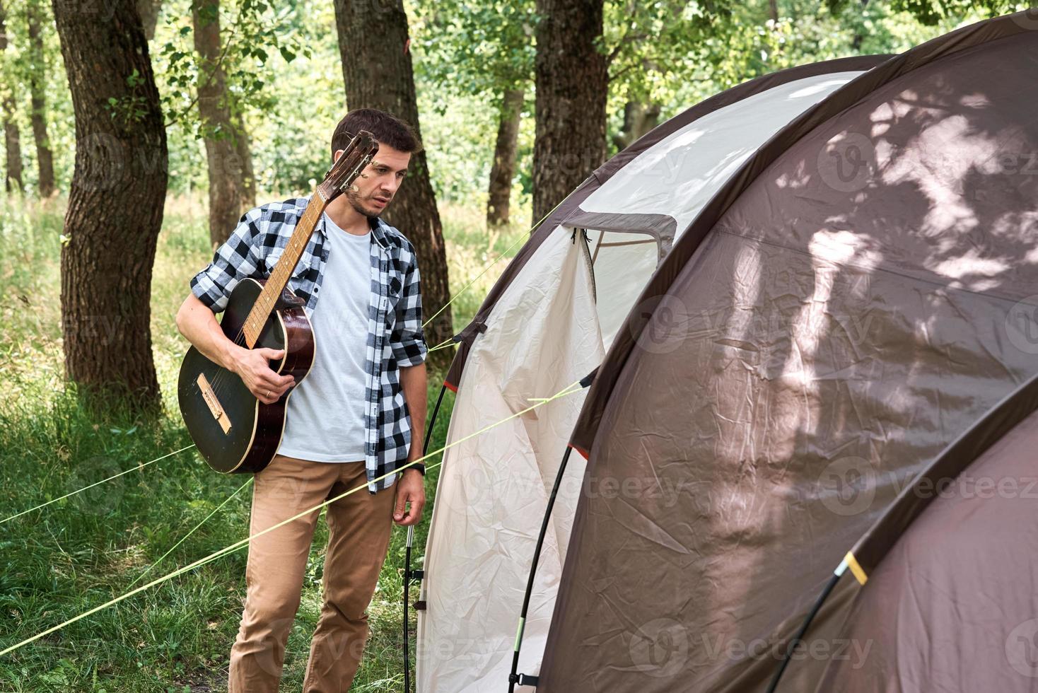 Tourist man with guitar near camping tent photo