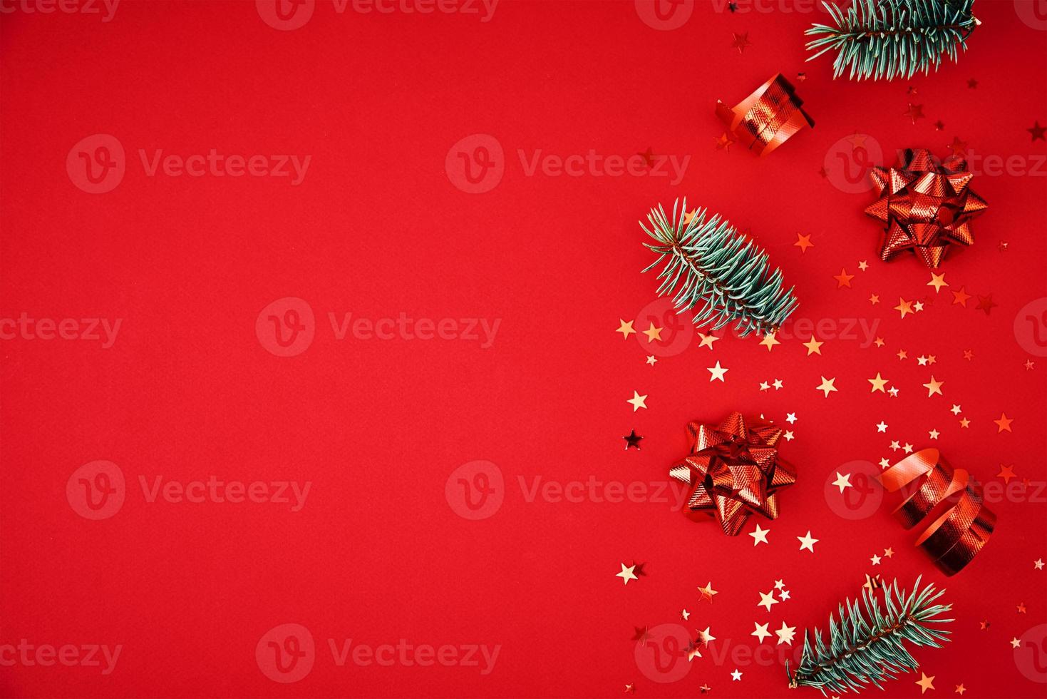 Fir branches, pine cones, dried fruits and festive confetti on a red background photo
