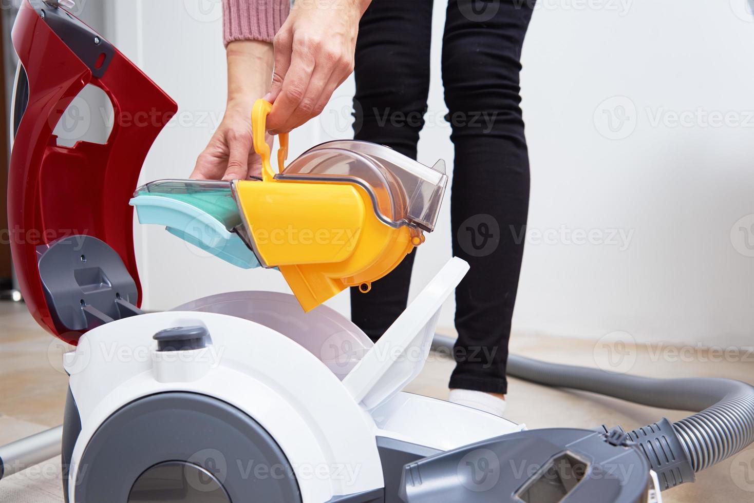 Woman takes out container of dust from vacuum cleaner photo