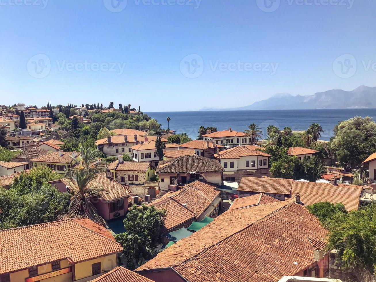 view of the green city from above. houses with even roofs of yellow tiles. vacation at the seaside resort. local stone houses photo