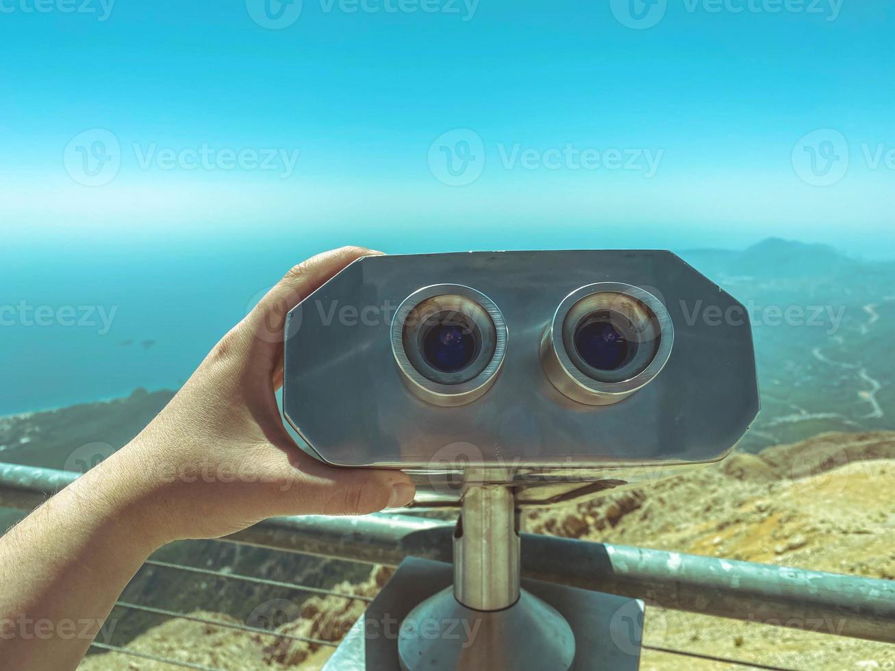 a viewing platform with binoculars with large black lenses against the sky. environment magnifier. panoramic binoculars for tourists, a man holds it with his hand photo