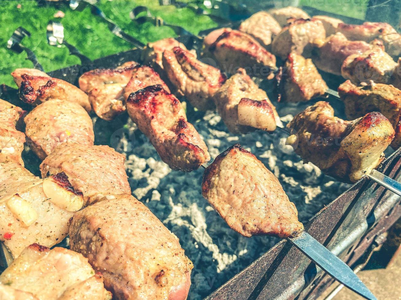 meat kebab on skewers lies on the grill. a crust is baked on pieces of meat. grilled dishes, barbecue in the courtyard of the house. cooking dinner photo