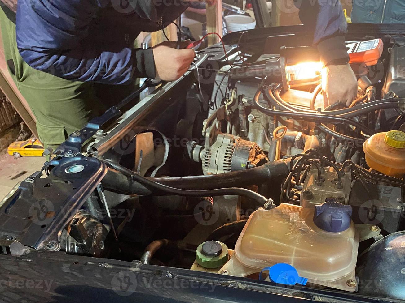 maestro cerrajero reparador de trabajo repara un coche bajo el capó en un taller en un garaje foto