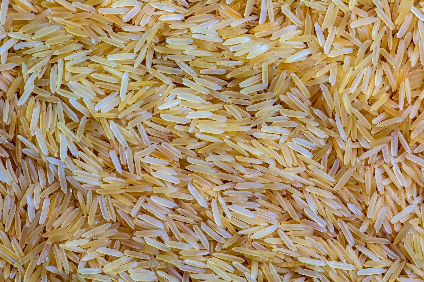 Background of long grain parboiled uncooked rice. Rice groats as background and texture. photo