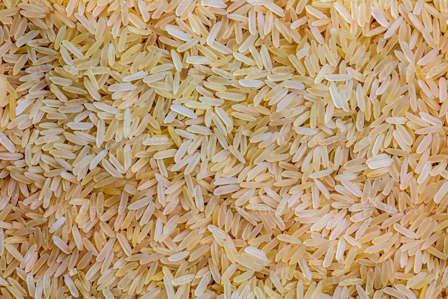 Background of long grain parboiled uncooked rice. Rice groats as background and texture. photo