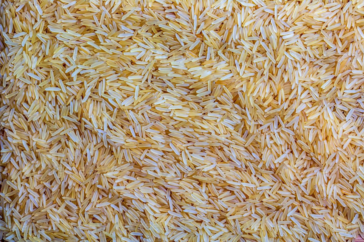 Background of long grain parboiled uncooked rice. Rice groats as background and texture. photo