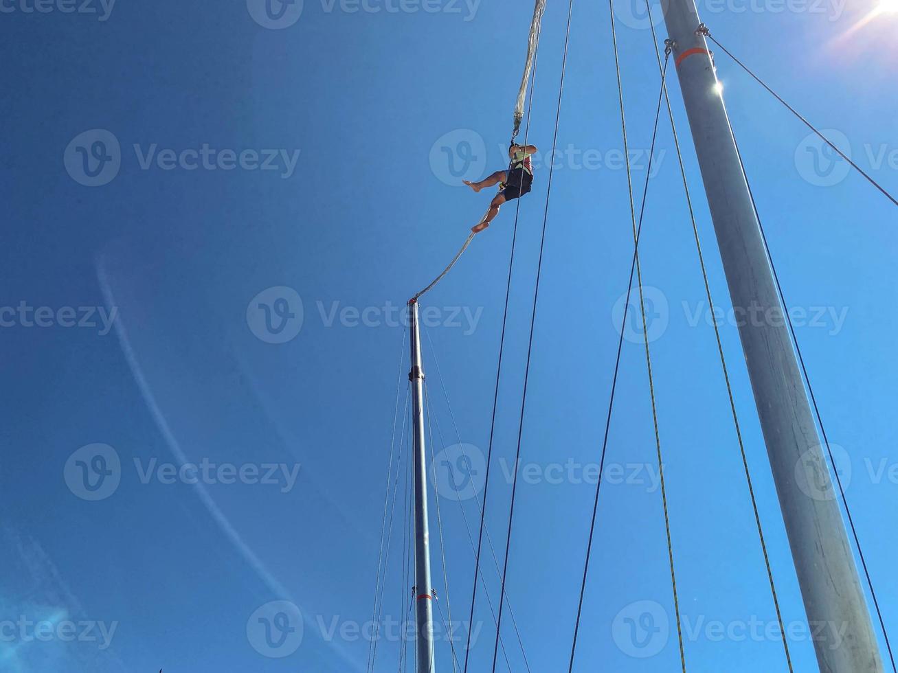 catapult on top of the mountain. entertainment for tourists, active recreation. jump up on a huge elastic band, a man in equipment in a catapult against the blue sky photo