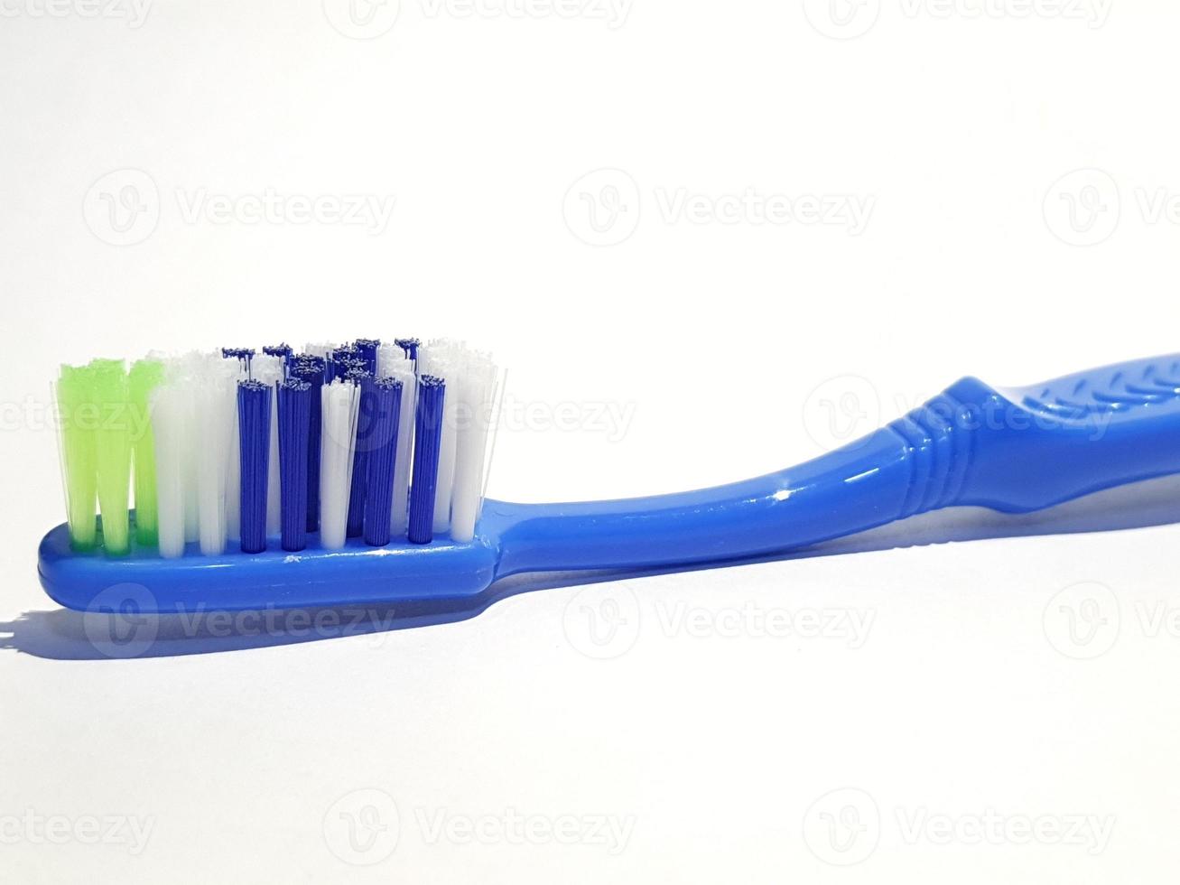 Isolated white photo of a plastic toothbrush that has been used several times. This toothbrush has a blue handle.