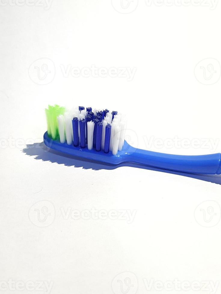 Isolated white photo of a plastic toothbrush that has been used several times. This toothbrush has a blue handle.