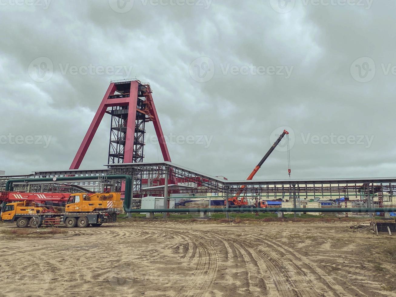 mining complex. metal drill to search for minerals in the ground. construction at the industrial site of the plant. nearby construction cranes and equipment, the construction of the complex photo