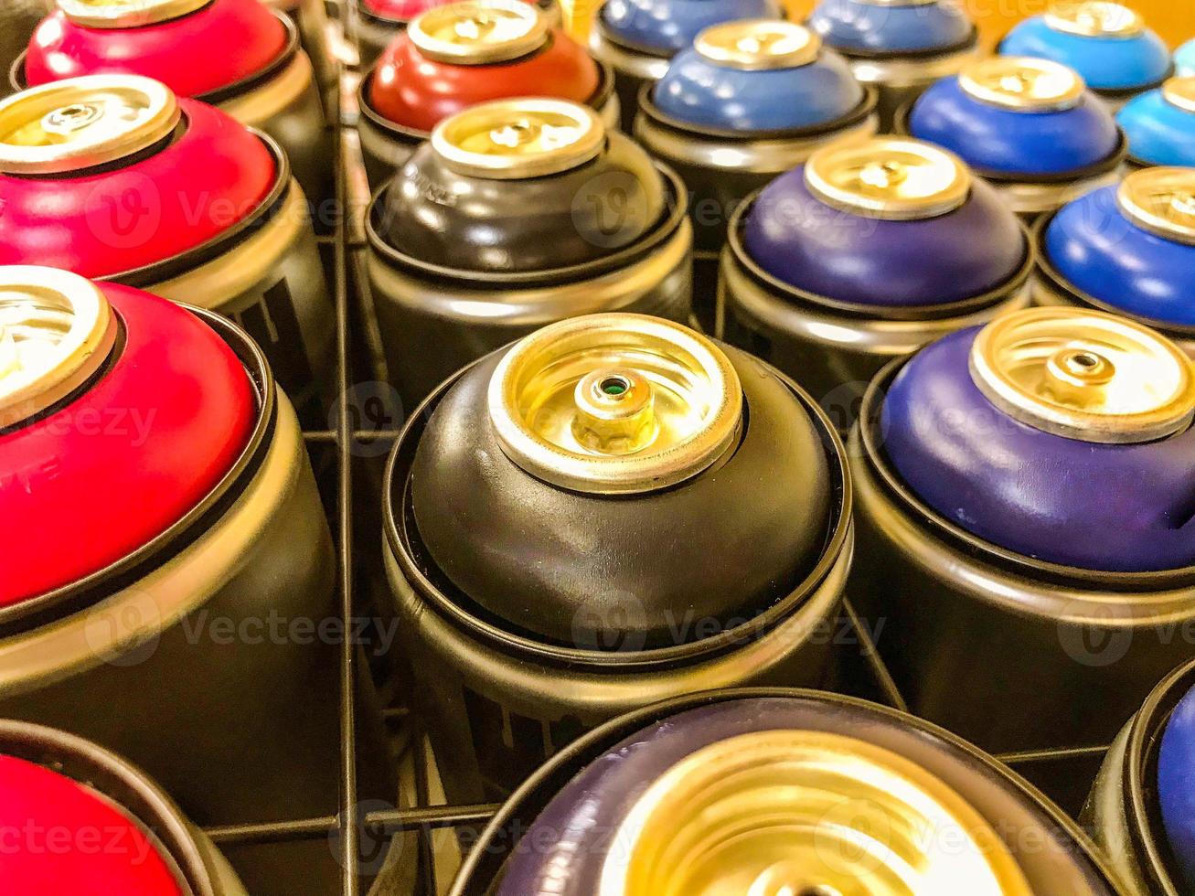 las latas de aerosol de pintura se exhiben detrás de una malla metálica. pulverizadores de pintura de varios colores. graffiti, pintura de autos. los globos están llenos de tintes multicolores para la creatividad foto