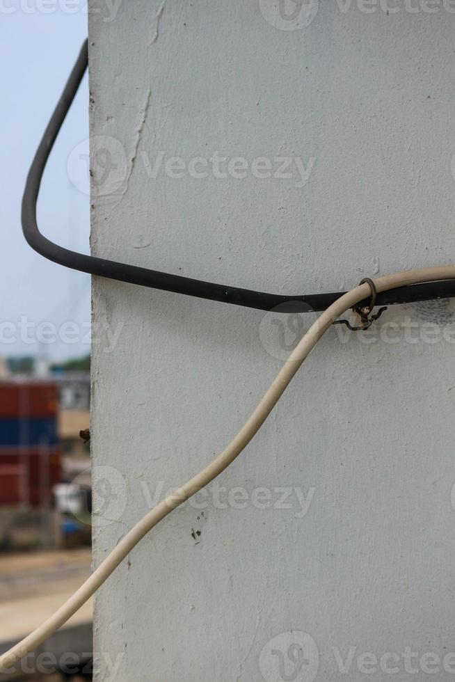 White cable and black cable attached to the wall photo