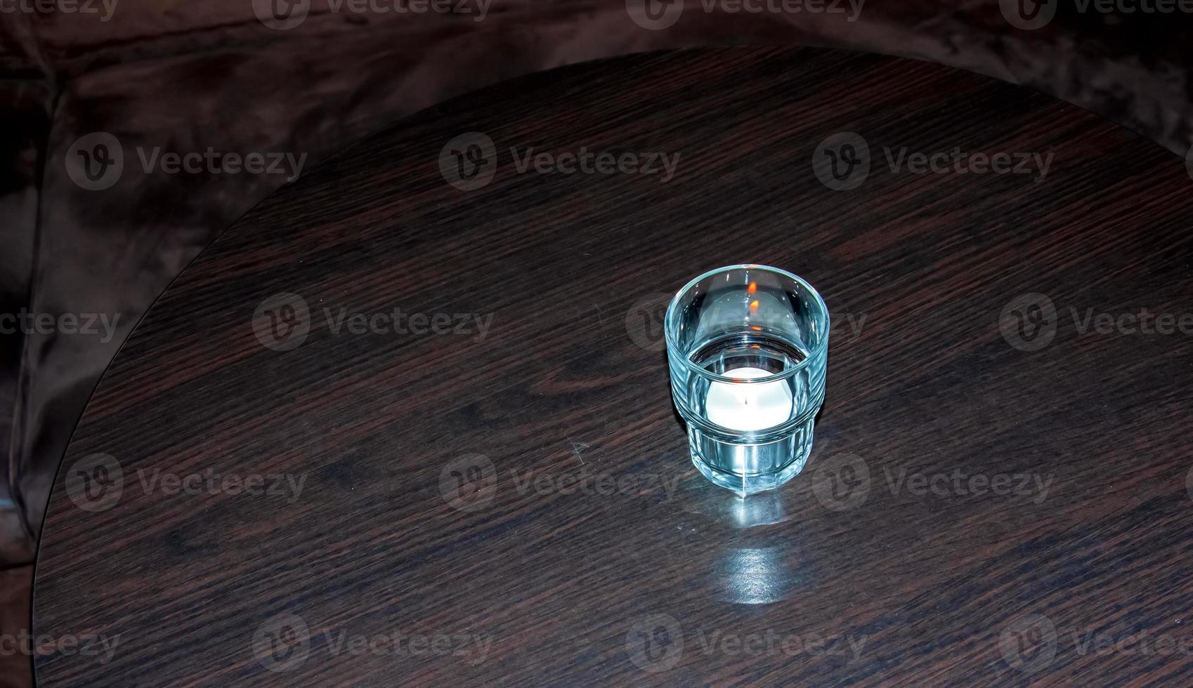 A burning scented candle on a wooden table to create a relaxing atmosphere during dinner. photo