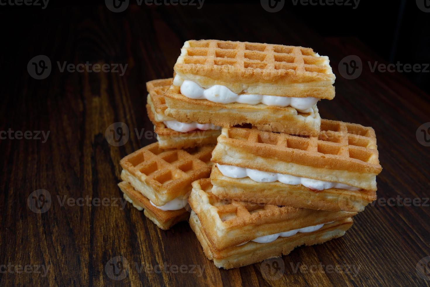 Delicious fresh Viennese waffles with white cream lie on a wooden table. photo