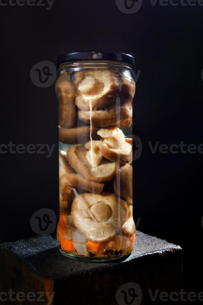 Pickled mushrooms with spices in a glass jar . Salted homemade mushrooms . Rustic food . photo