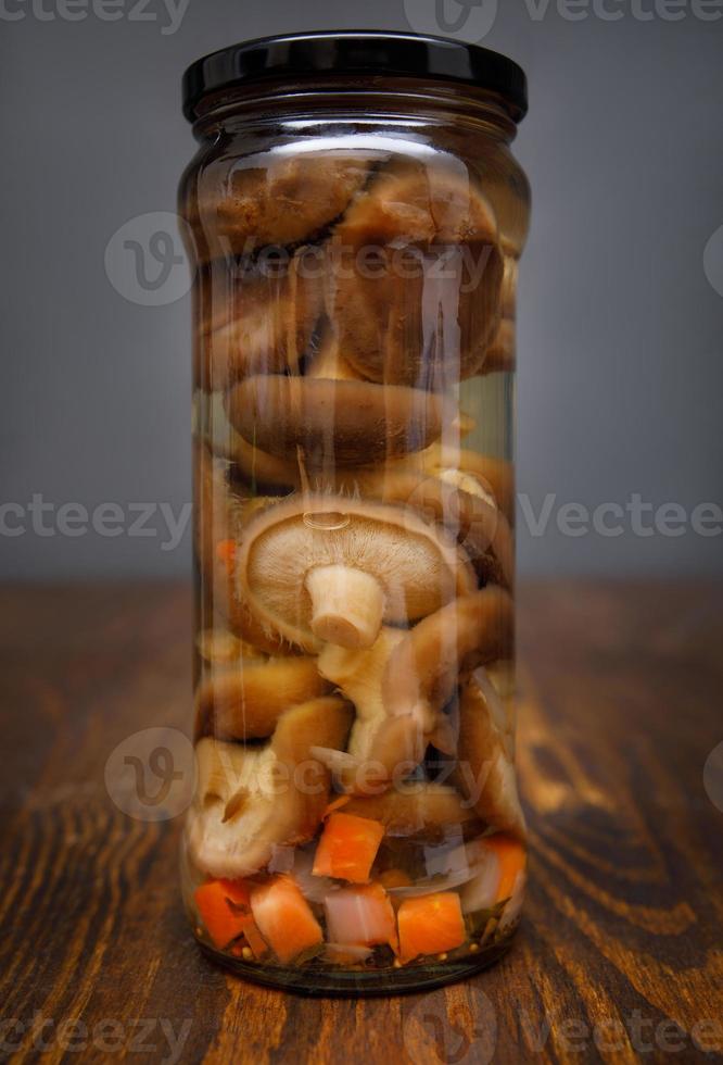 Pickled mushrooms in a glass jar . Salted homemade mushrooms . Rustic food . photo