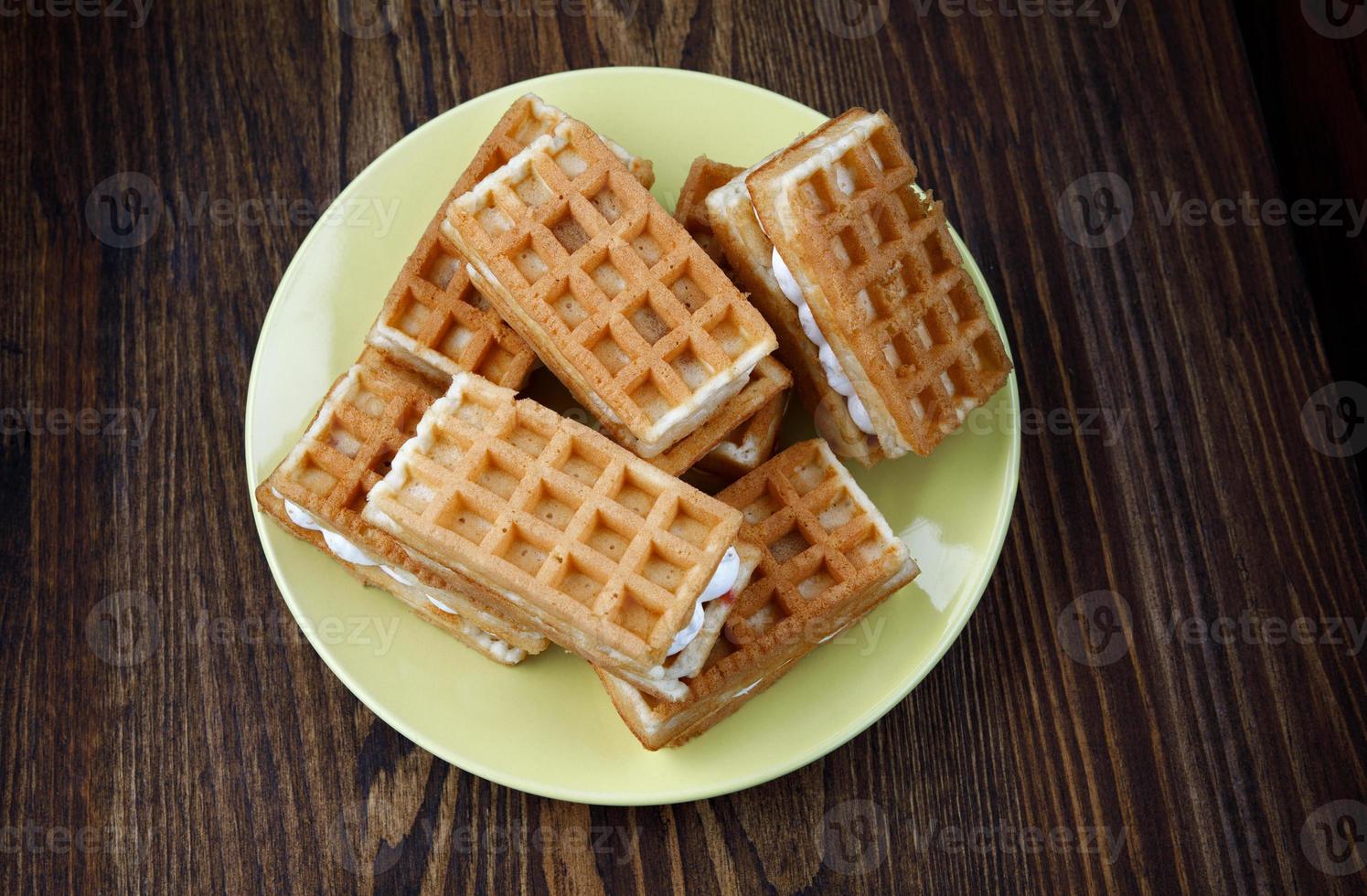 A pile of fresh Viennese waffles lie on a yellow plate. photo
