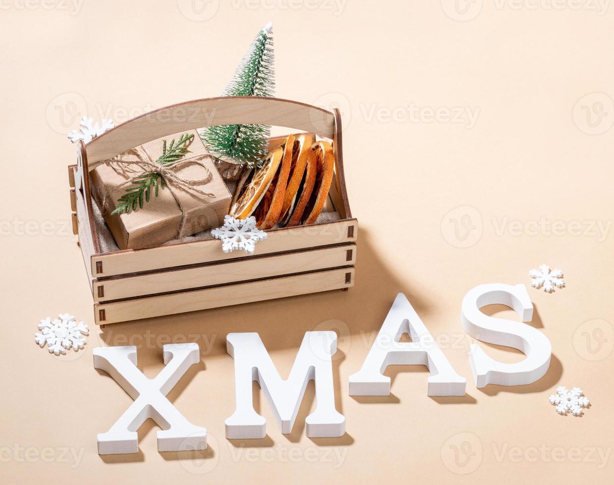 Christmas decorations in wooden box and white letters XMAS on beige backdrop close up. photo