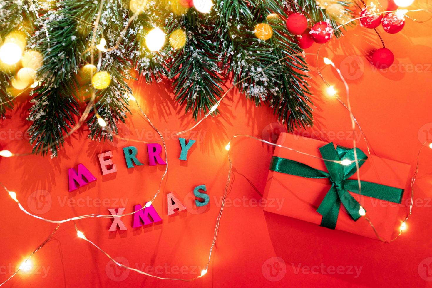 Fir branches, Christmas lights, snow, red berries, color letters Merry Xmas, DIY gift box, golden bokeh lights on red. photo