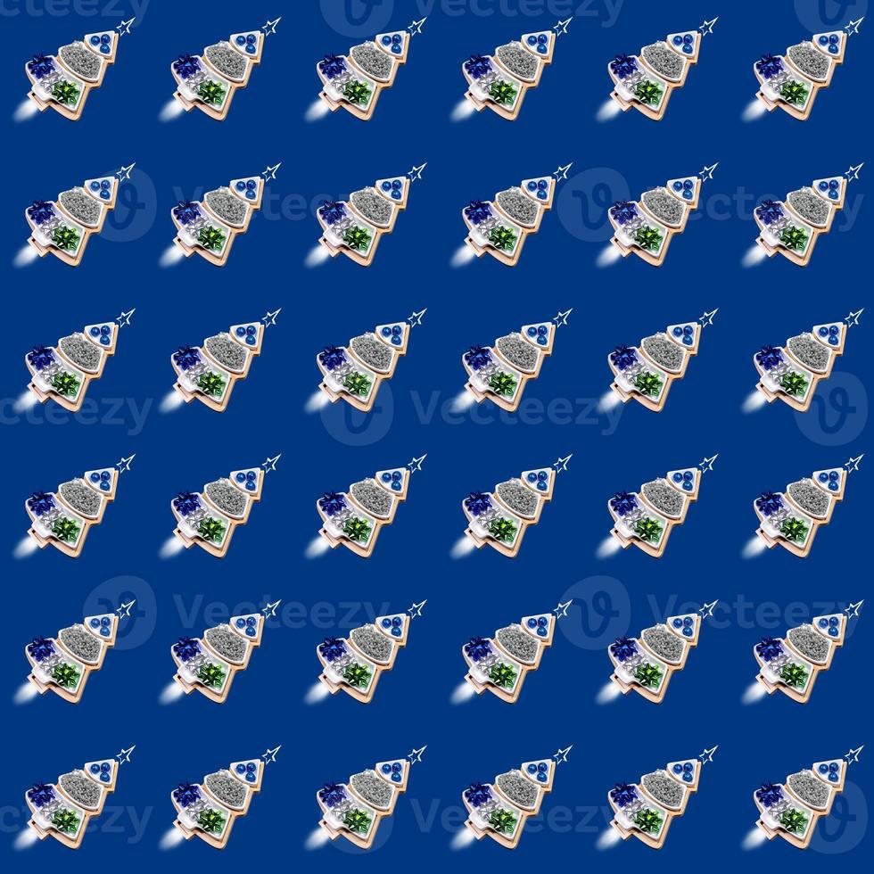 Funny seamless pattern of plates of Xmas trees shape with Xmas decorations as rockets on blue. photo