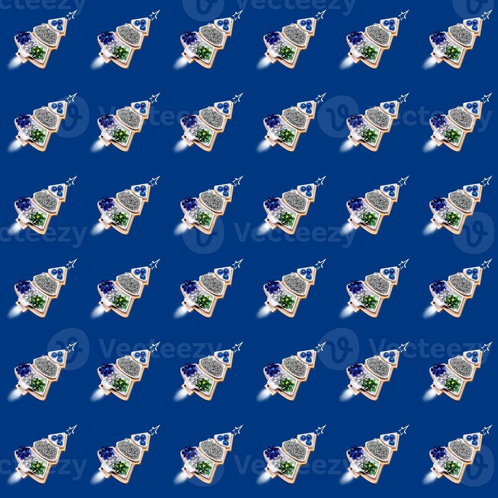 Funny seamless pattern of plates of Xmas trees shape with Xmas decorations as rockets on blue. photo