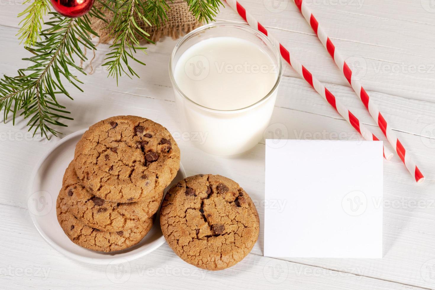 Christmas traditional milk for Santa with straws, cookies, empty blank note on white wooden table. photo