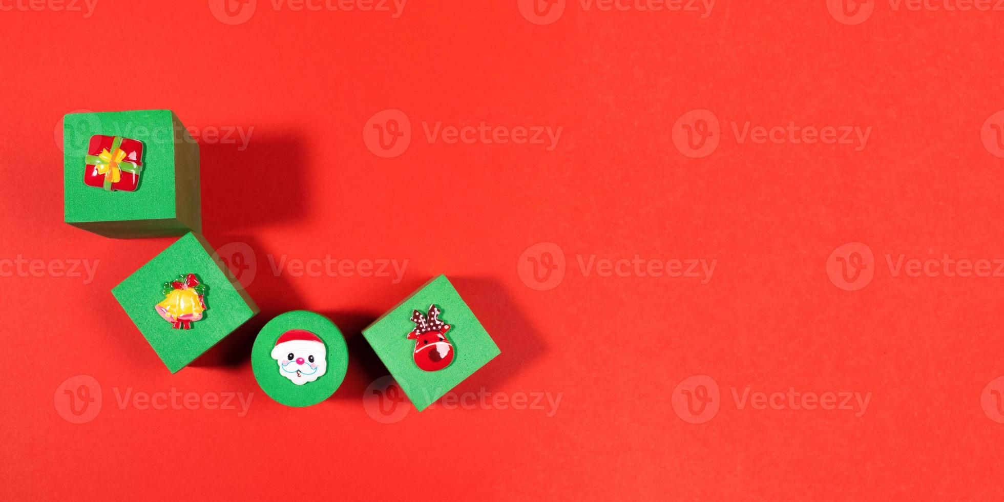 Festive banner with four green soft toys children's cubes with Xmas symbols above on them on red background with copy space. photo