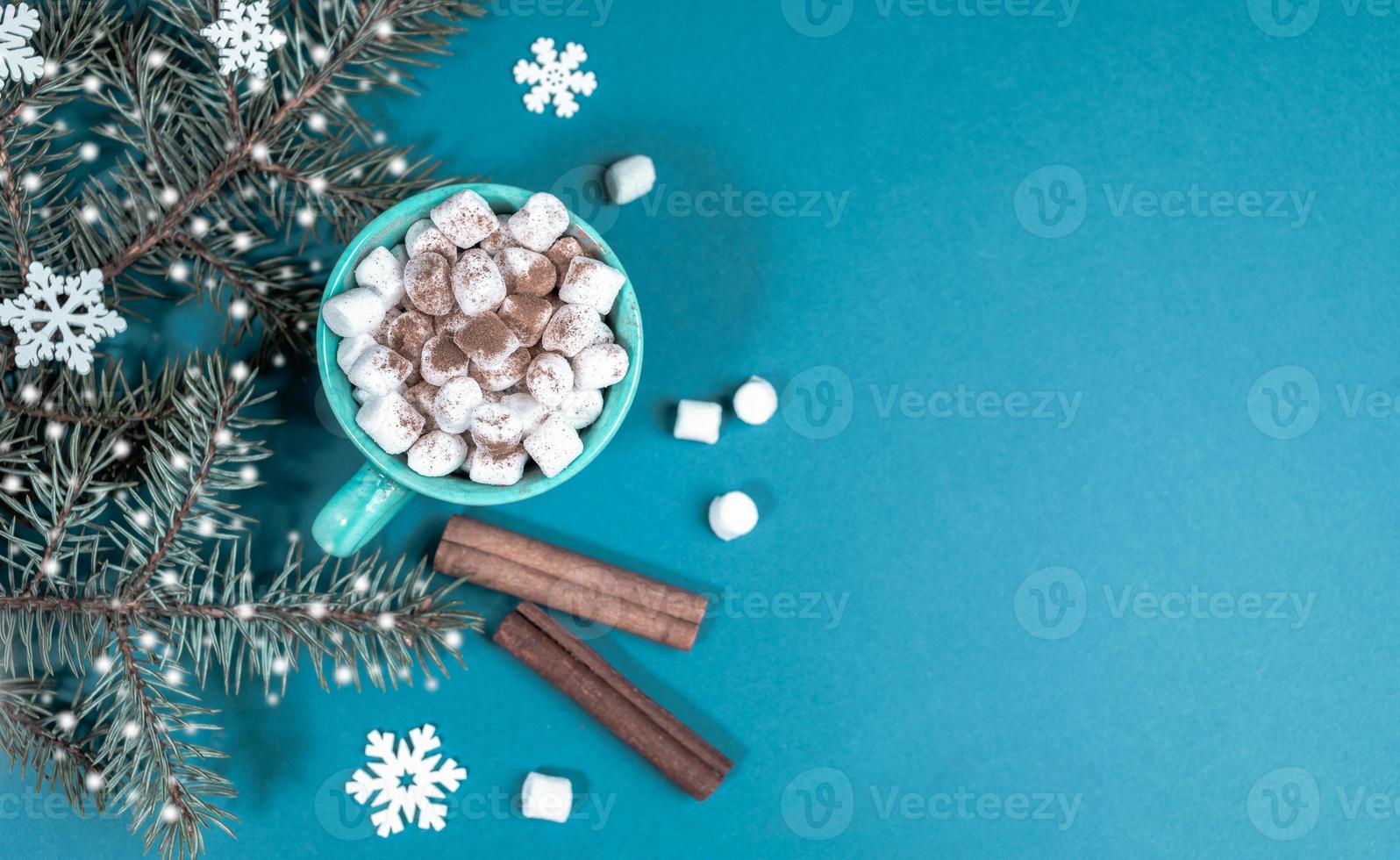 Turquoise Christmas background with fir branches with snow and cup of coffee or cocoa with marshmallows. Top view. photo