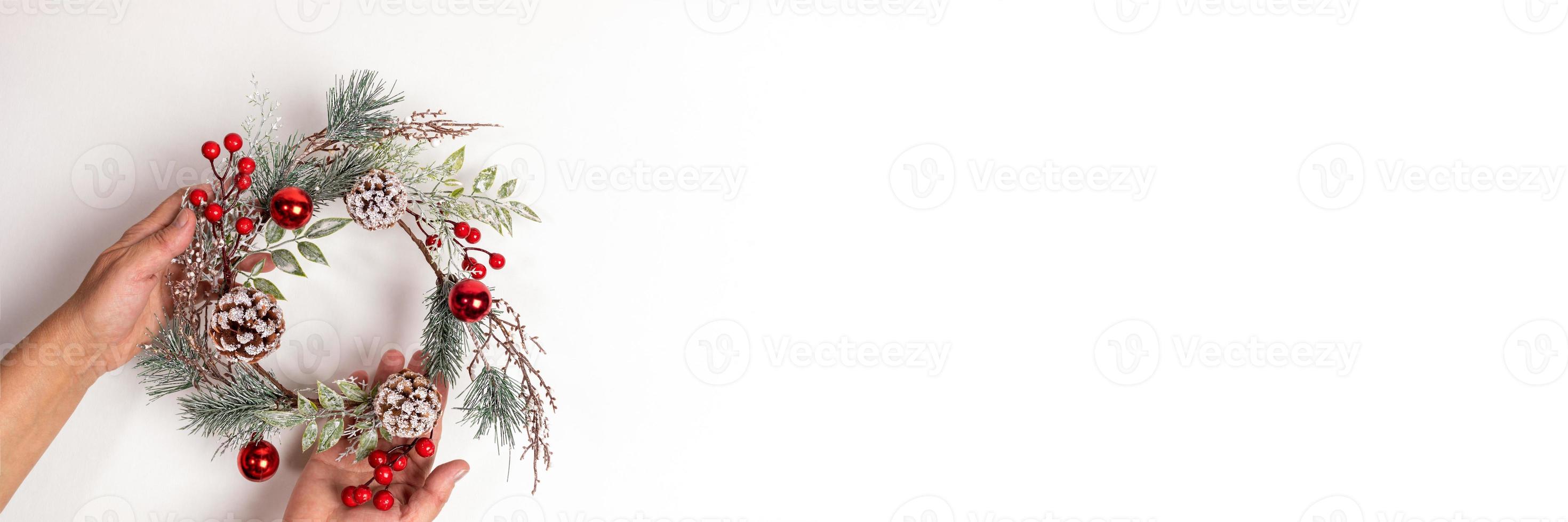 Xmas festive wide banner with woman hands holding handmade reusable Christmas wreath on white backdrop with copy space. photo