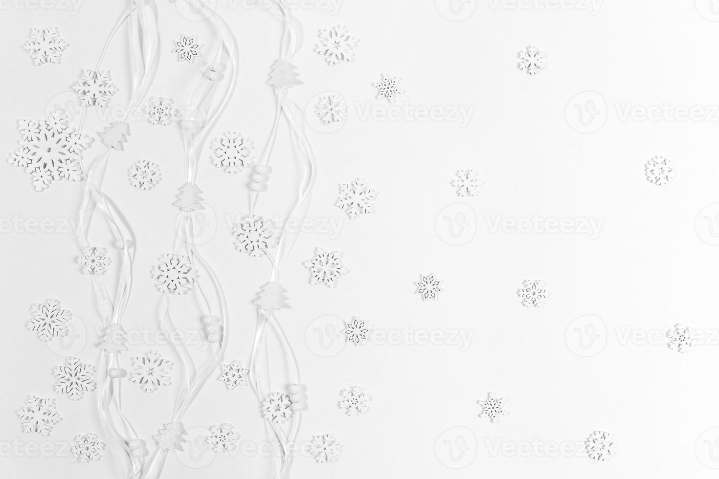 Christmas white background made of white wooden snowflakes and small Christmas trees and round beads on narrow ribbons. photo