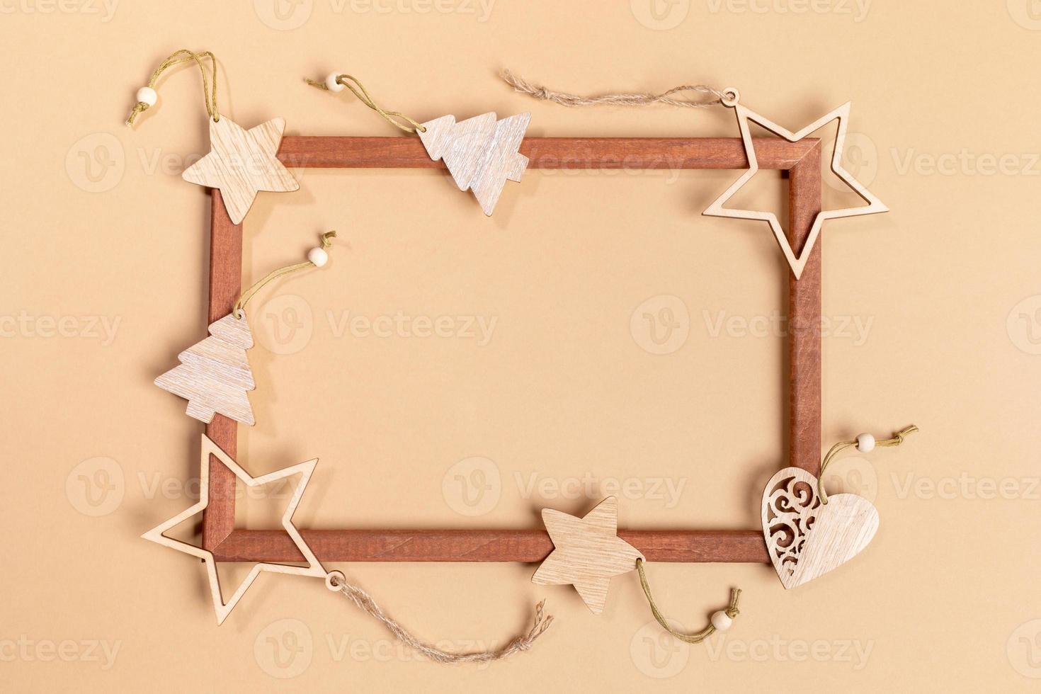 Christmas festive mock up with wooden festive decorations on empty wooden frame on beige with copy space inside it. photo