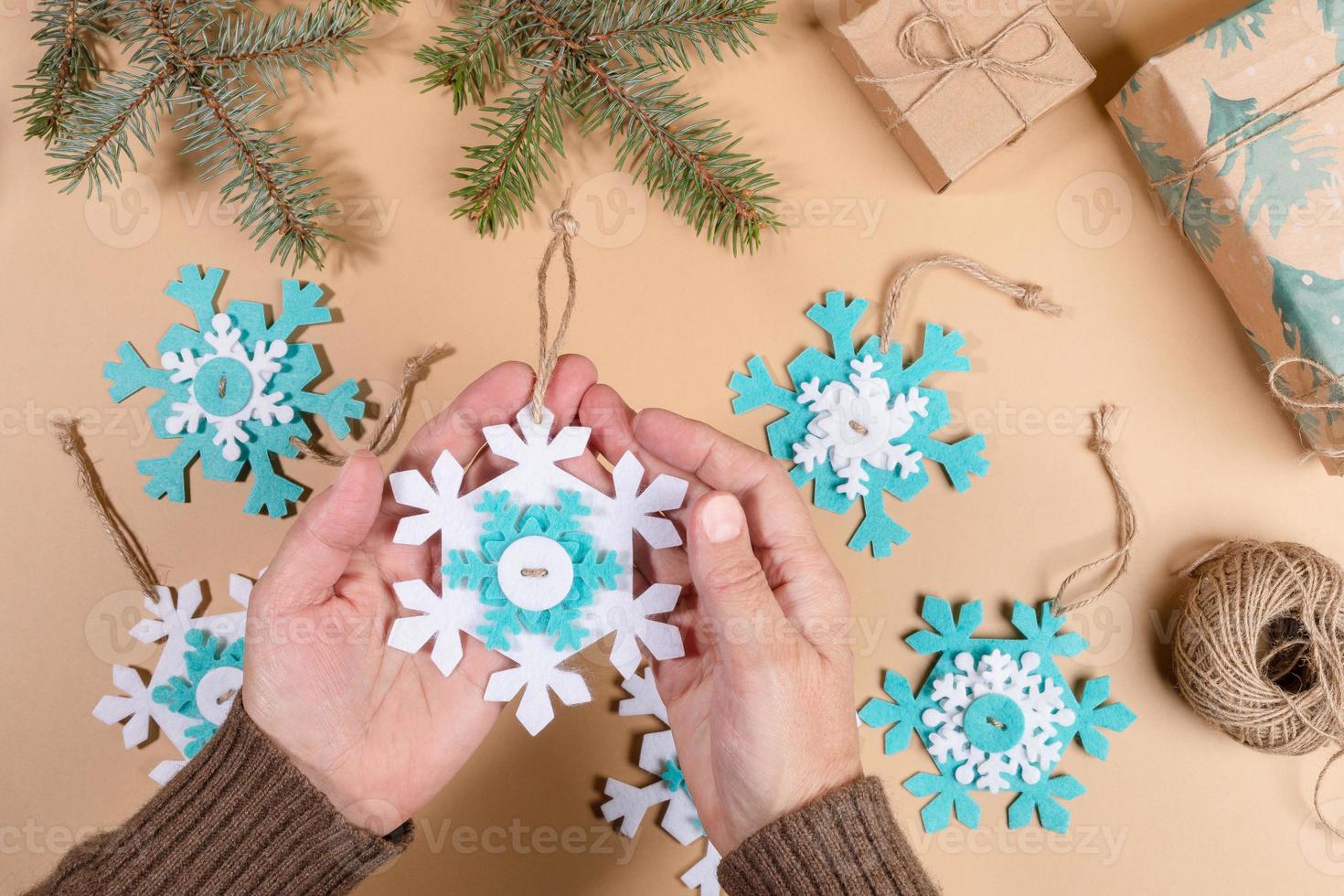 Step by step instruction of make DIY Xmas toy snowflake. Step 7 - Tie threads on snowflakes in knots. Flat lay. photo