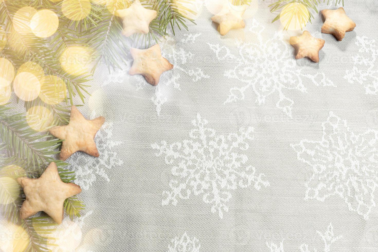 Homemade cookies of stars shape on grey towel with snowflakes as backdrop and with bokeh lights. photo